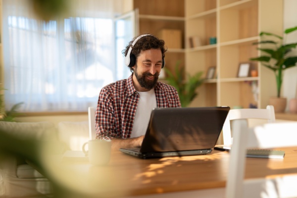 Homme avec un casque travaillant sur son ordinateur chez lui