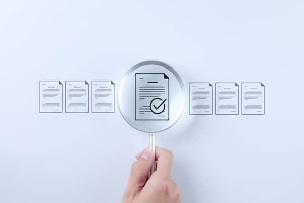 Main tenant une loupe au-dessus d'une rangée de documents