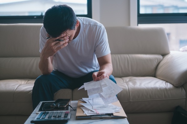 Homme stressé examinant ses factures sur son canapé